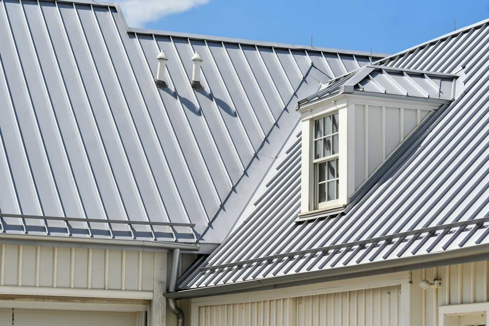 Grey metal roof, white siding, and a dormer window